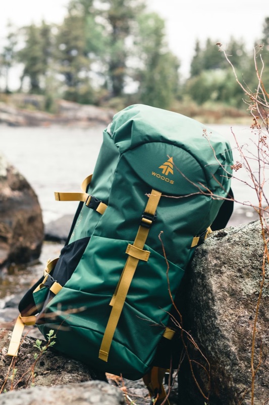 Green hiking backpack resting against granite boulders by a river